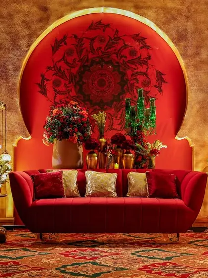 The central red sofa, perfectly staged with floral arrangements and traditional lanterns. This vignette serves as a focal point, embodying the theme's blend of comfort and opulence.
