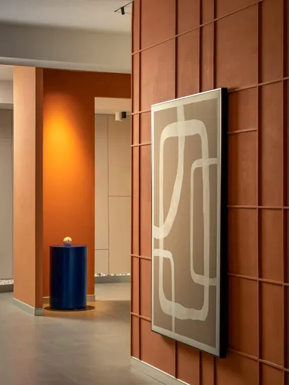 A closer look at the custom wall art and terracotta paneling. The abstract art piece complements the linear grid of the wall, adding a softer, graphic element to the space.