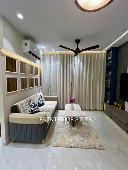 This living room shows a comfortable sofa with custom cushions and a modern TV unit with a display shelf. The wall behind the sofa features decorative niches, adding a unique design element.