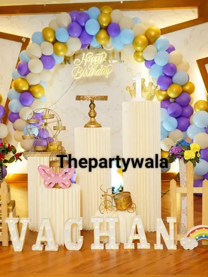 A full view of a purple, blue, and gold balloon ring setup with large photo cutouts of the birthday boy.