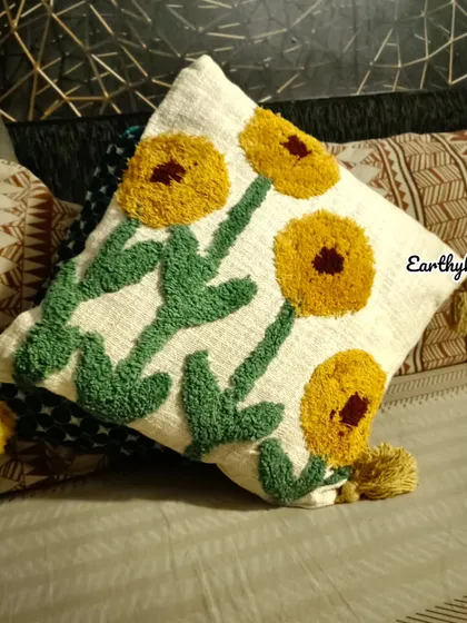 A close-up of the sunflower cushion cover on a bed, showing its plush texture and how it pairs with other patterns.