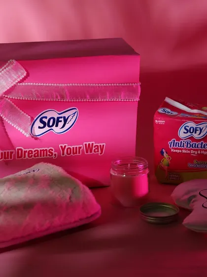 The complete Sofy PR hamper, featuring a custom box, sanitary products, a cozy pouch, and a scented candle, all tied together with a beautiful ribbon.