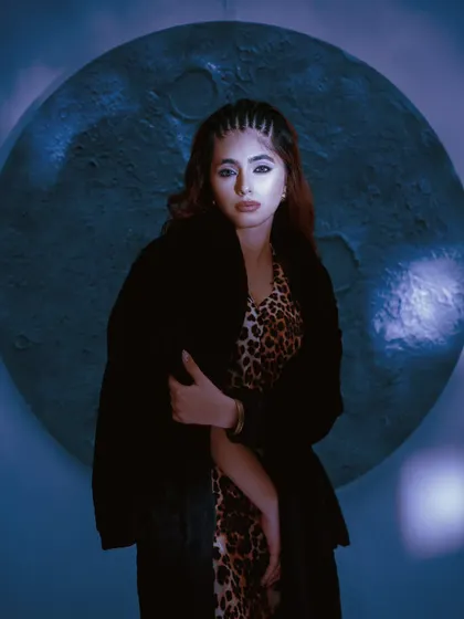 A full-look shot with dramatic, cool-toned lighting. The styling and background create a celestial, high-fashion mood for a model's book.