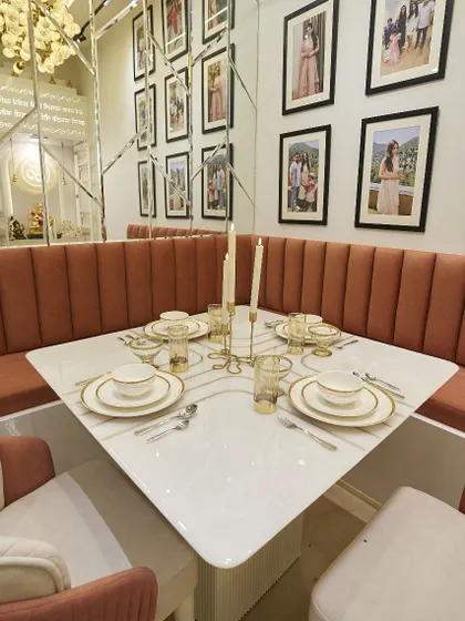 A close-up of the beautifully set dining table. The white and gold dinnerware complements the elegant and warm theme of the space.