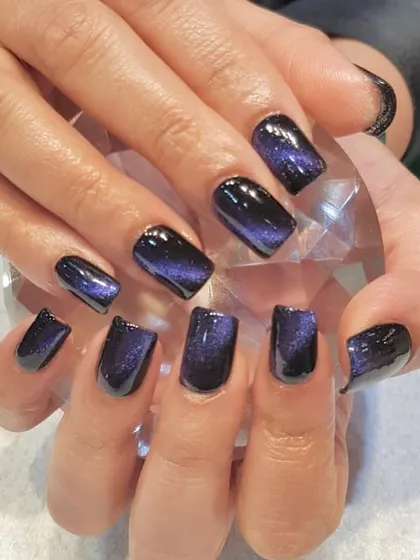 Stunning cat-eye nails in a deep, galactic purple. The magnetic polish creates a beautiful, shimmering effect that looks like a nebula on your fingertips.