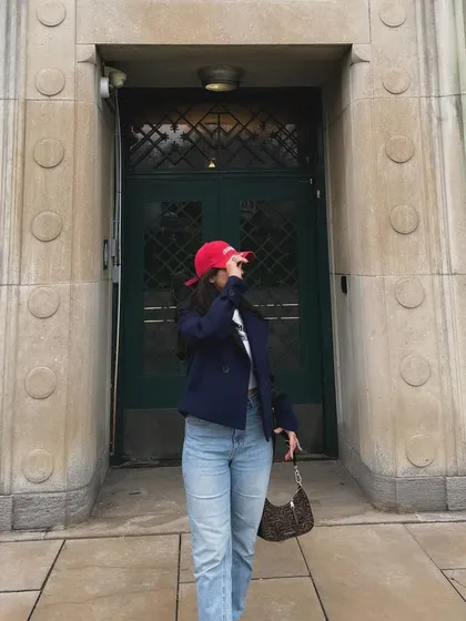 A playful pose, adjusting my cap, in my easygoing weekend look.