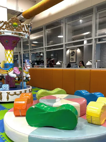 A view of the carousel and the soft, colorful seating nearby, with the parent's cafe visible in the background.