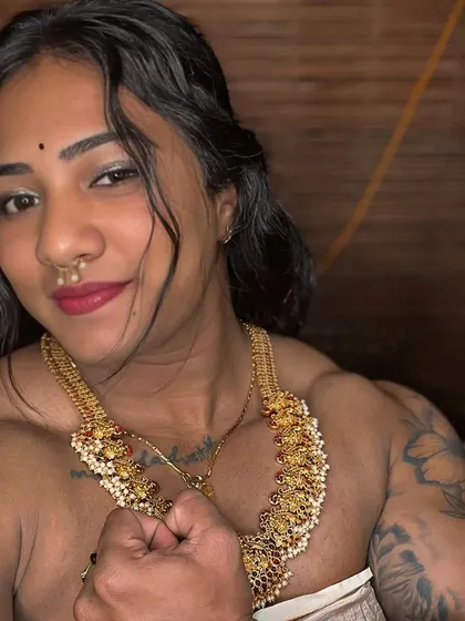 A close-up shot focusing on the details of the traditional jewelry and my confident expression, with my defined deltoids and trapezius muscles clearly visible.