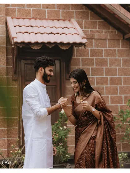 A playful and happy moment between a couple, captured against the rustic charm of a brick house during their pre-wedding shoot.