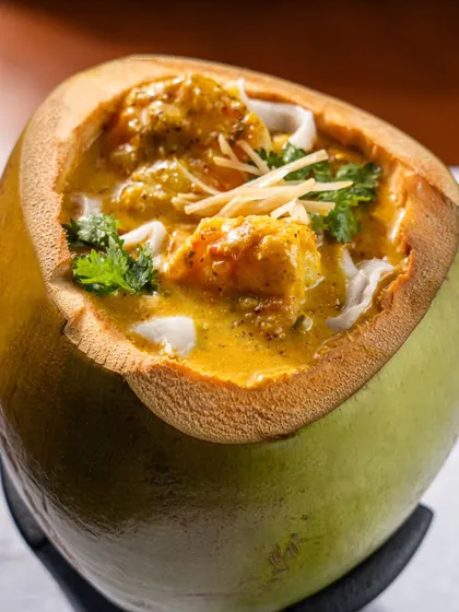 A creamy curry served inside a fresh green coconut at Gallops. This unique presentation is highlighted to showcase the restaurant's creative approach.