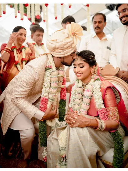 A tender moment as the groom, Athmic, kisses his bride, Sushma, on the forehead during their wedding ceremony.