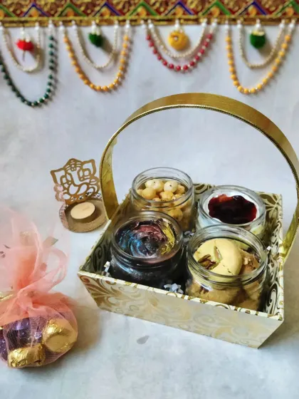 My Diwali hamper is a basket full of joy, combining sweet and savory treats. It includes two of my homemade cake jars, a jar of crunchy peri peri makhana, traditional pistachio nankhatai, and a little pouch of assorted chocolates.