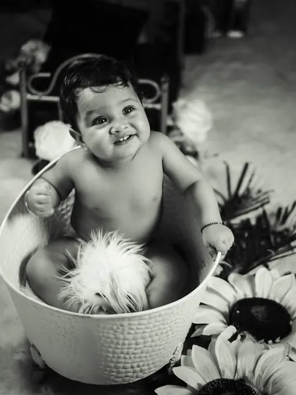 A fun and safe splash time shoot. This black and white photo highlights the joy of our bathtub setup, which includes a classic white tub and surrounding floral props for a touch of whimsy.