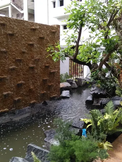 Another view of the stone waterfall and pond, showing the gentle movement of water and the naturalistic rock placements that mimic a riverbank.