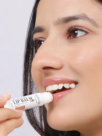 This is a close up, action oriented shot showing a model applying lip balm. This type of image is highly effective for demonstrating product use and highlighting its moisturizing benefits.