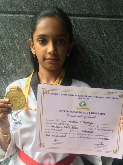 A gold medal win for our student Mrudula at the CISCE National Sports & Games. This photo captures her pride in holding her certificate of merit and medal.