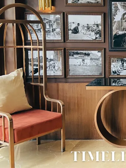 This image showcases a timeless furniture piece, a high-backed accent chair with a birdcage-like frame. It's set against a gallery wall of black-and-white photos, blending classic elegance with modern design.
