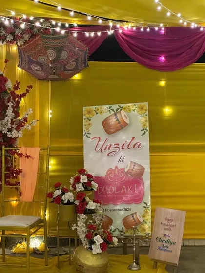 A personalized welcome sign for 'Uzaila ki Dholki'. The sign is part of a larger terrace setup, adding a custom touch to the pre-wedding celebration.