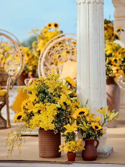 A beautiful arrangement of sunflowers and lilies in rustic terracotta vases, perfect for a sun-drenched outdoor event.
