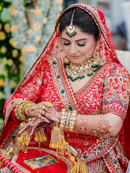 A bride getting ready, her hands adorned with henna and kaleeras, perfectly complementing her red rental lehenga.