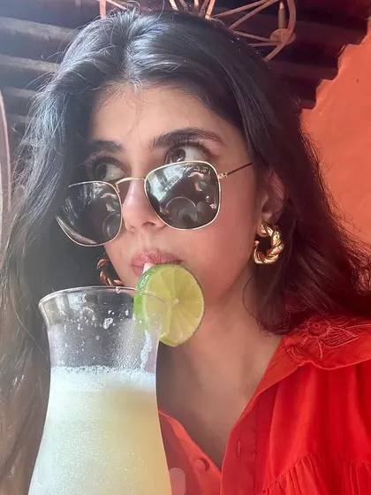 Sanjana Sanghi enjoying a drink, looking cool and casual in the Braided Beauty Hoops. Proof that great style doesn't have to be complicated.