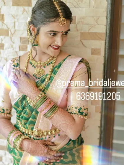 This happy bride is wearing a beautiful temple jewellery set with green stone accents, which perfectly matches her green and pink saree.