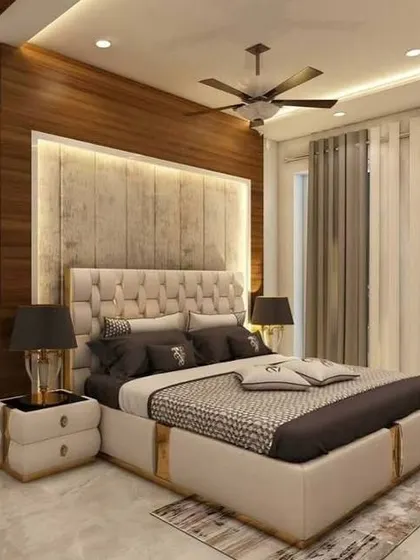 This luxurious bedroom design features a large, tufted headboard with a backlit wood panel. The matching bedside tables and lamps create a symmetrical and harmonious look.