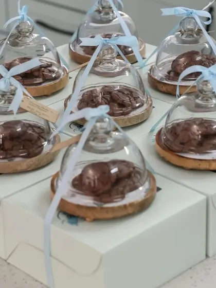 Edible favors are always a hit, especially when presented this beautifully. Here, fresh-baked cookies are placed on a wooden coaster and covered with a glass cloche, then tied with a ribbon.