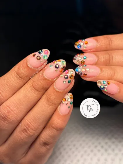 A fun and colorful take on the crystal trend. This design features a nude base with a cluster of multi-colored gems at the tips for a playful and eye-catching look.