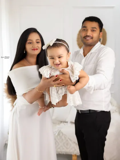 A playful and happy family photo, with the parents holding their giggling baby. This shot captures the fun and energy of family life.