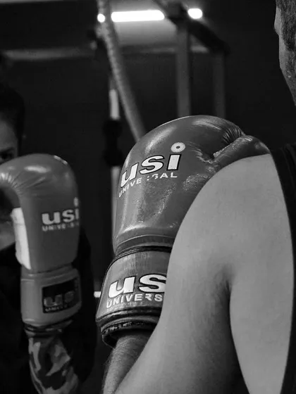A female boxer practicing her defense against a partner. Her eyes are focused, anticipating the next move.
