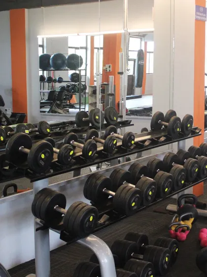 Our dumbbell rack, with weights for all strength levels, is neatly organized against a mirrored wall. This setup allows you to easily monitor your form during exercises like bicep curls or shoulder presses.