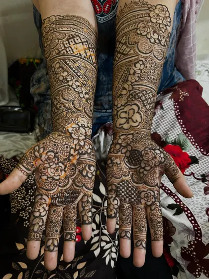 A personalized bridal design featuring the initials 'SR' cleverly hidden within the floral patterns on the palm. The rest of the design is packed with fine details and traditional motifs.