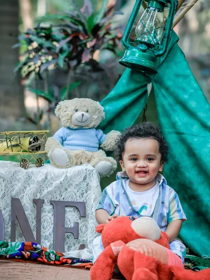 Celebrating a first birthday with a camp-themed setup in the park. The little one's happy smile is the centerpiece of this adventurous portrait.