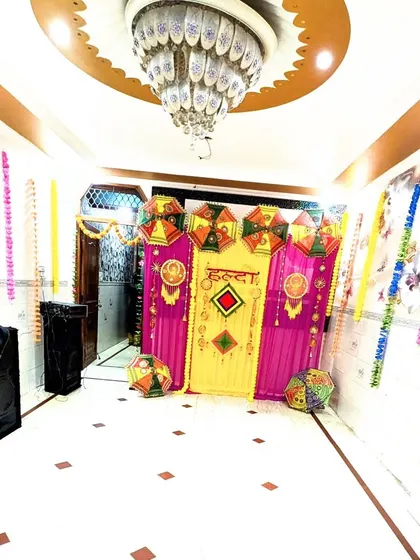 A fisheye lens view of the Haldi setup, capturing the entire festive corner from the ornate chandelier to the decorated floor.
