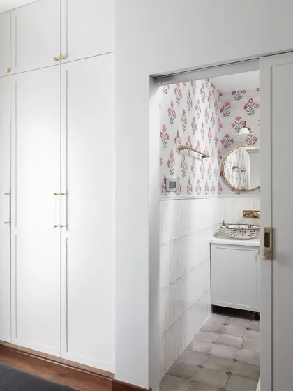 A peek from a bedroom into an en-suite bathroom in the Madras Home. The design shows how we create cohesive private suites, with details like pocket doors to save space.