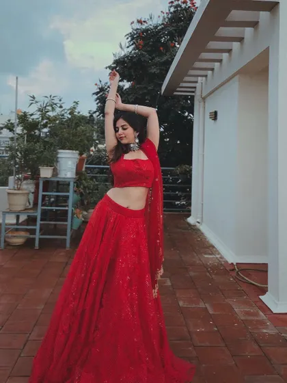 A dynamic pose in the red lehenga, capturing its movement and energy.