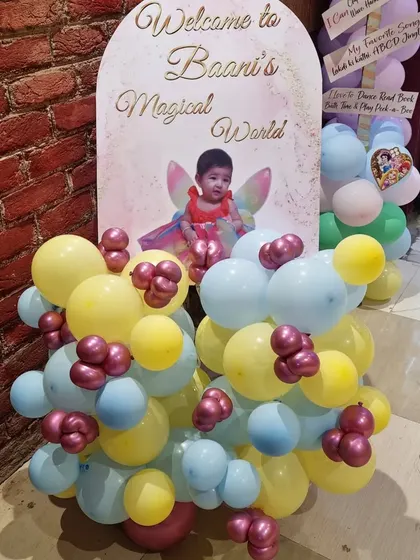 A custom welcome board for "Baani's Magical World," decorated with a small balloon garland.