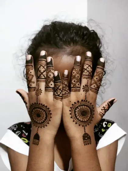 A fun design for a child, featuring a central mandala with a hanging charm and detailed geometric fingers.