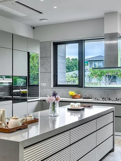 This handle-less kitchen in an Ahmedabad residence showcases contemporary luxury. The sleek, minimalist design in a custom RAL matt lacquer finish, combined with a spacious island, creates a space that is both highly functional and visually serene.