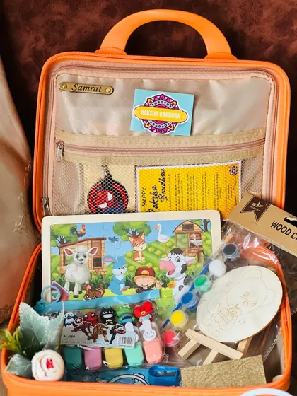 A closer look at the arts and crafts supplies inside the Rakhi suitcase, including a puzzle, wood crafts, and paints.