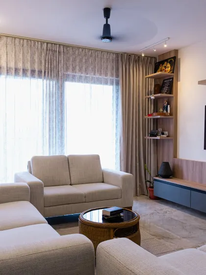 A cozy and contemporary living room setup. The neutral-toned sofa, wicker coffee table, and smart corner shelving unit create a balanced and inviting space perfect for everyday living.