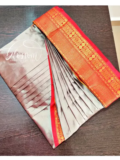 This is the final result of my pre-pleating and box folding service. The pleats are set, and the saree is folded to prevent wrinkles, making it incredibly easy to wear. This grey and red saree is ready for my client.