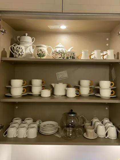 A cabinet dedicated to a beautiful collection of teapots, cups, and saucers. We arranged them by set, creating an elegant display that is ready for high tea.