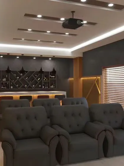 A home theater design that includes a dedicated bar area. The room features comfortable recliner chairs, dark acoustic panels, and focused lighting for an authentic cinema feel.