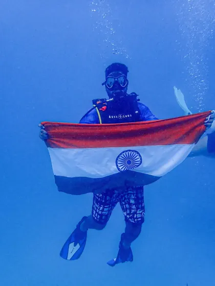 A diver in our group proudly displays the Indian flag underwater to mark the 75th Independence Day, a memorable part of our dive holiday.