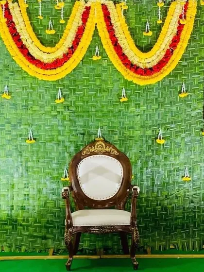 A simple yet beautiful backdrop made entirely of natural materials. The wall of woven green leaves is decorated with marigold garlands, making it a perfect, budget-friendly option for engagements and naming ceremonies.