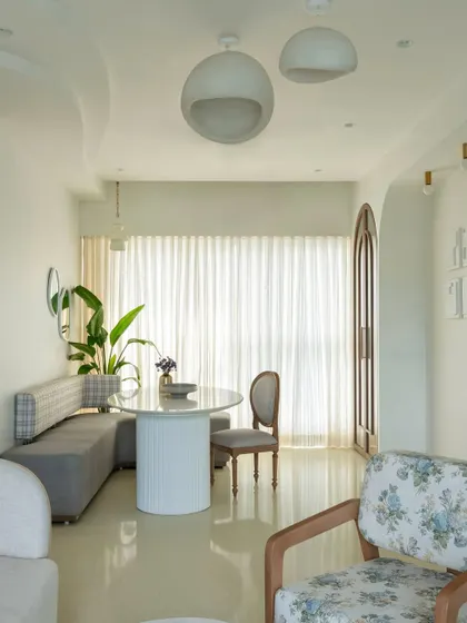 The open layout of this home creates a feeling of spaciousness and light. The dining nook flows seamlessly into the living area, with a cohesive palette of whites, greys, and natural wood tones tying the different zones together.