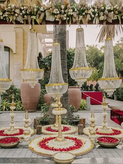 A majestic entrance designed for a day wedding. This setup combines the grandeur of suspended chandeliers with the rustic charm of pampas grass and a traditional floral rangoli.