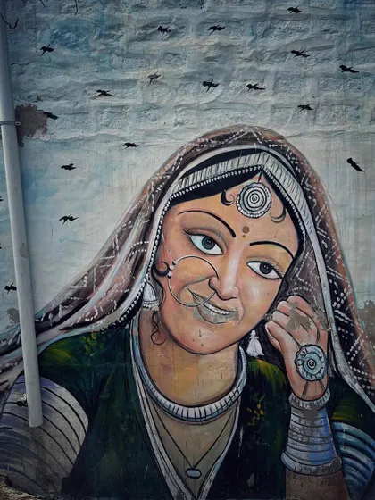 A mural of a smiling Rajasthani woman in traditional attire, her expressive eyes and gentle smile adding color to a wall in Jodhpur.